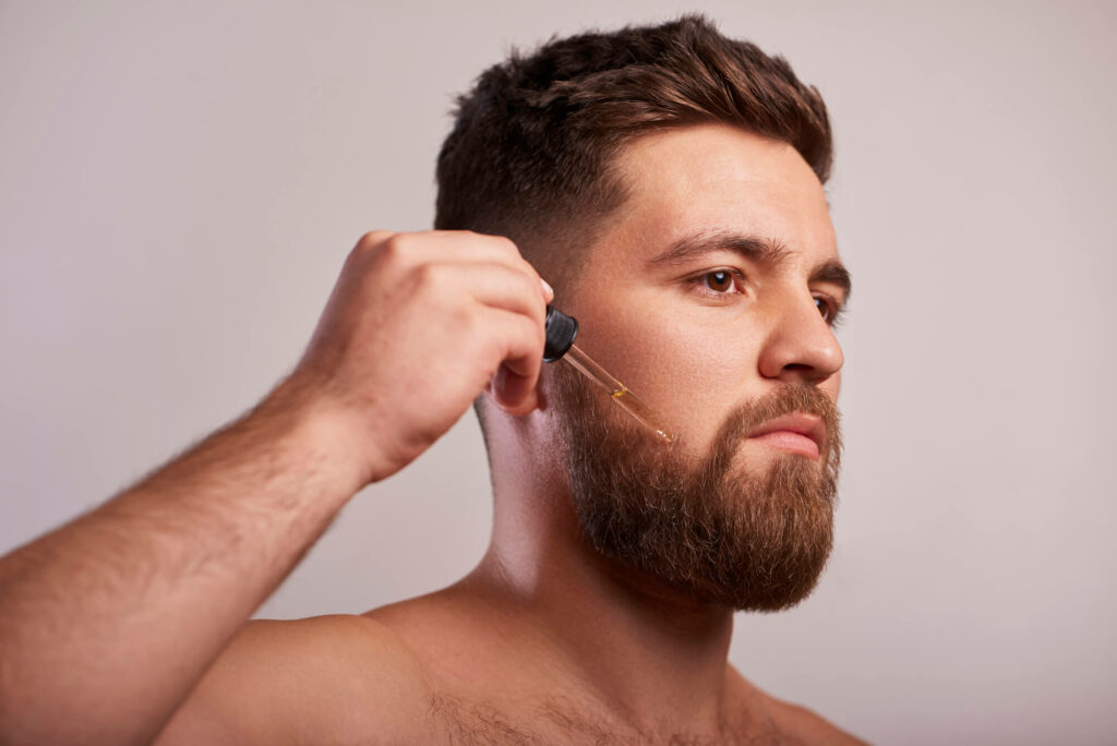 A man puts beard oil on his beard