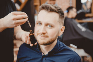 Barber applies beard oil with dropper for man in barber shop