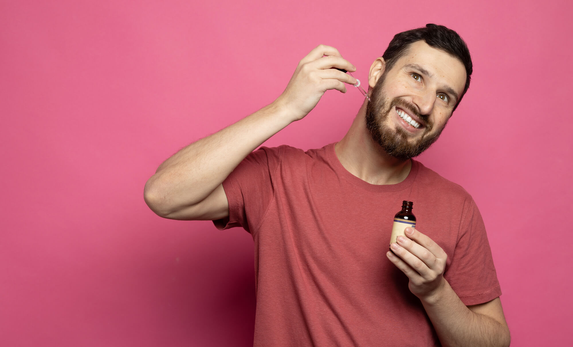 Bearded man holding pippete with beard oil